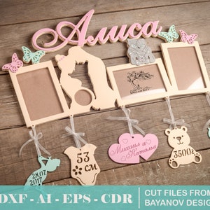 Op de afbeelding: Een houten fotolijst met de naam "Alisa" in roze letters. De lijst heeft meerdere openingen voor foto's en bevat verschillende decoratieve elementen, zoals vlinders, een teddybeer, een baby-romper en een klok. De lijst is ontworpen voor een babykamer.