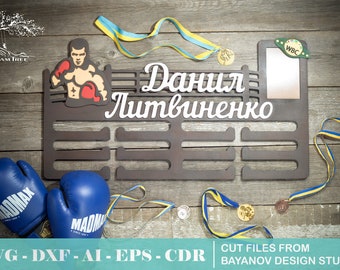 May include: A wooden medal display rack with the name "Данил Литвиненко" in white lettering. The rack has 10 slots for medals and a small rectangular space for a photo or other memorabilia. There are two blue boxing gloves with the word "MADMAX" on them, a yellow and blue ribbon, and a gold medal with the letters "WBC" on it.