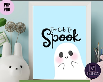May include: Printable wall art featuring a cute ghost with the text "Too Cute To Spook" in black lettering on a light blue background. The ghost has a pink blush on its cheeks and a happy expression.