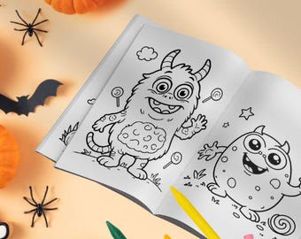 May include: Open coloring book featuring monster illustrations with a Halloween theme. The pages are filled with line art of friendly monsters, lollipops, and stars. Crayons in various colors are scattered around the book, along with pumpkins and spider decorations.