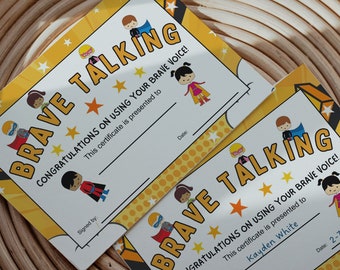 Puede incluir: Dos certificados de superhéroes amarillos y negros con el texto "Brave Talking" y "¡Felicidades por usar tu voz valiente!" El certificado de la izquierda tiene el texto "Este certificado se entrega a" y el certificado de la derecha tiene el texto "Este certificado se entrega a Kayden White".