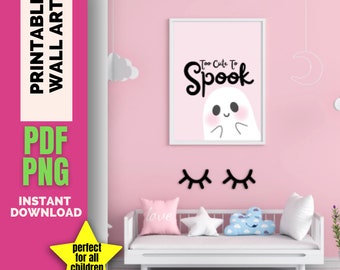 May include: A pink wall featuring a framed print with the text "Too Cute To Spook" and a ghost illustration. Below are black eyelash decorations. A white couch has pillows with the word "love", a star, and a cloud.