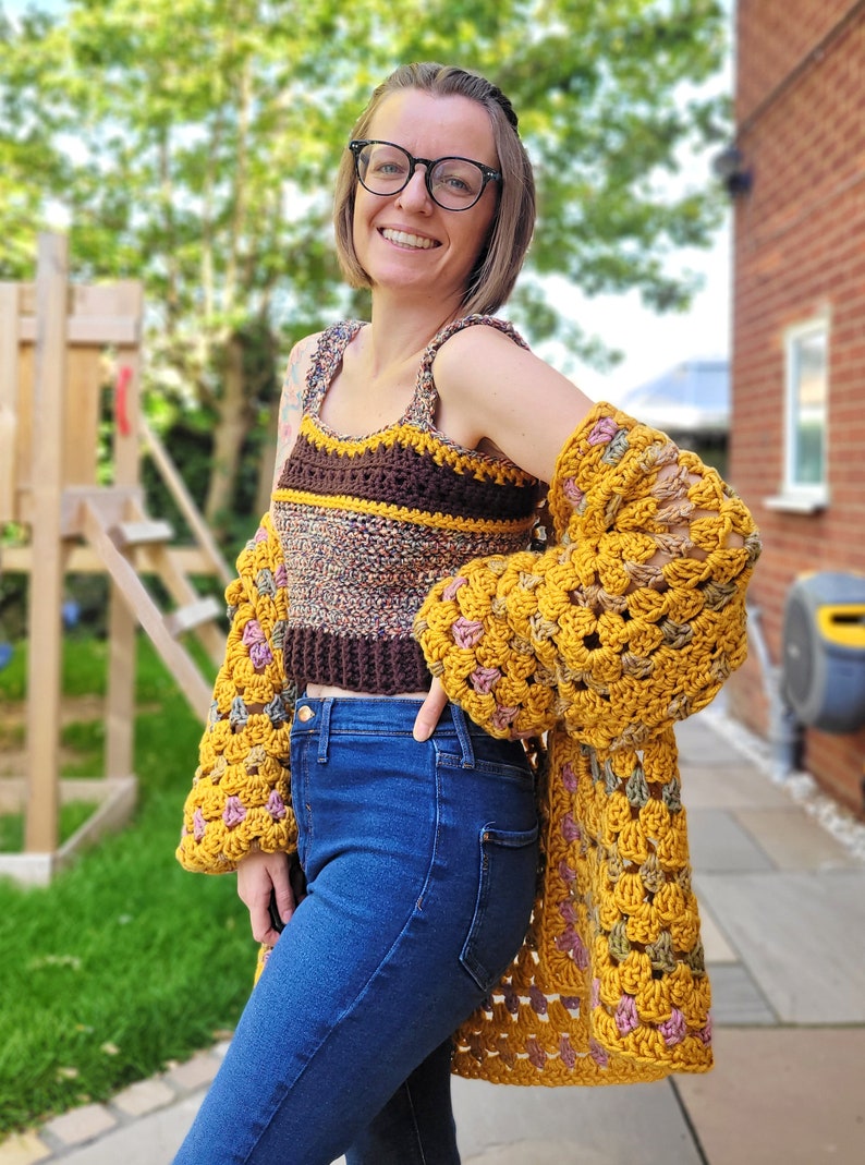 K&ouml;nnte beinhalten: Eine Frau tr&auml;gt ein braunes und gelbes gestreiftes H&auml;keltop mit einer gelben H&auml;keljacke. Sie tr&auml;gt eine blaue Jeans und hat die Hand auf der H&uuml;fte.