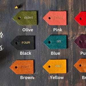 May include: Leather swatches in eight different colors: olive, pink, red, black, blue, purple, brown, and yellow. Each swatch has a number from one to eight written on it.