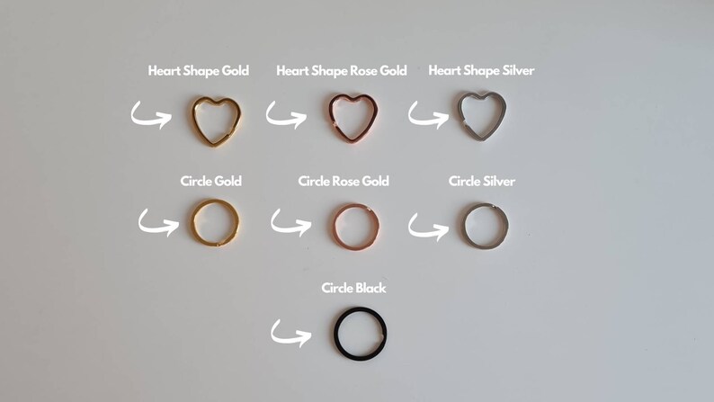 May include: A set of six key rings in different shapes and colors. The key rings are in the shape of a heart and a circle. The colors are gold, rose gold, silver, and black.