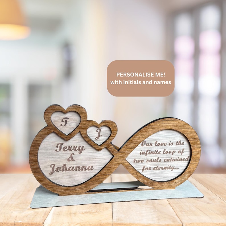 Puede incluir: S&iacute;mbolo de infinito de madera con dos corazones, personalizado con los nombres "Terry & Johanna" y las iniciales "T" y "J". El s&iacute;mbolo de infinito tiene el texto "Nuestro amor es el bucle infinito de dos almas entrelazadas por la eternidad..."