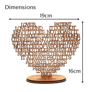 May include: Wooden heart-shaped decorative piece with the words "Love is Kind" and other phrases, measuring 7.5 inches wide and 6.3 inches tall. The piece is mounted on a wooden base and includes the names "Alison & Dan".