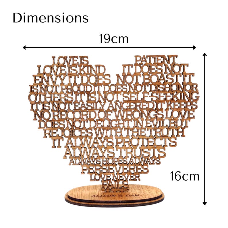 May include: Wooden heart-shaped decorative piece with the words "Love is Kind" and other phrases, measuring 7.5 inches wide and 6.3 inches tall. The piece is mounted on a wooden base and includes the names "Alison & Dan".