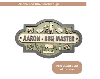 May include: Wooden BBQ Master sign with a gray border and green interior. The sign features various BBQ-related icons and the text "AARON - BBQ MASTER". The top of the sign reads "Personalised BBQ Master Sign".