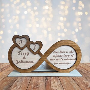 Puede incluir: S&iacute;mbolo de infinito de madera con dos corazones en el lado izquierdo y los nombres "Terry & Johanna" grabados en el interior. El lado derecho del s&iacute;mbolo de infinito tiene el texto "Nuestro amor es el bucle infinito de dos almas entrelazadas por la eternidad..." grabado.