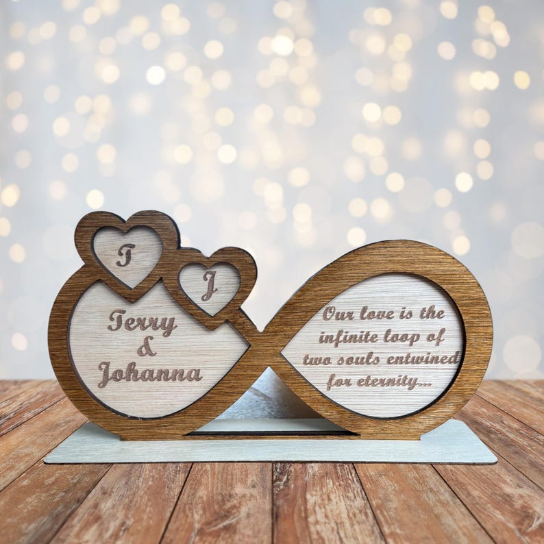 Puede incluir: S&iacute;mbolo de infinito de madera con dos corazones en el lado izquierdo y los nombres "Terry & Johanna" grabados en el interior. El lado derecho del s&iacute;mbolo de infinito tiene el texto "Nuestro amor es el bucle infinito de dos almas entrelazadas por la eternidad..." grabado.