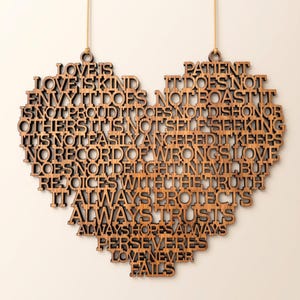 May include: A heart-shaped wall hanging made of dark brown wood, featuring laser-cut text that reads: Love is patient, love is kind. It does not envy, it does not boast, it is not proud. It does not dishonor others, it is not self-seeking, it is not easily angered, it keeps no record of wrongs. Love does not delight in evil but rejoices with the truth. It always protects, always trusts, always hopes, always perseveres. Love never fails.