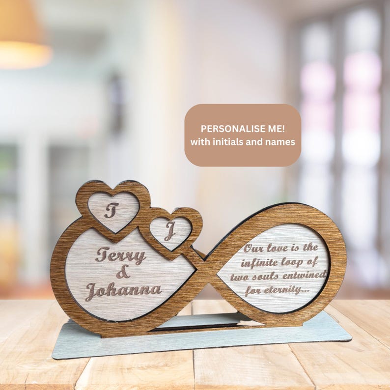 Puede incluir: S&iacute;mbolo de infinito de madera con dos corazones, personalizado con los nombres "Terry & Johanna" y las iniciales "T" y "J". El s&iacute;mbolo de infinito tiene el texto "Nuestro amor es el bucle infinito de dos almas entrelazadas por la eternidad..."