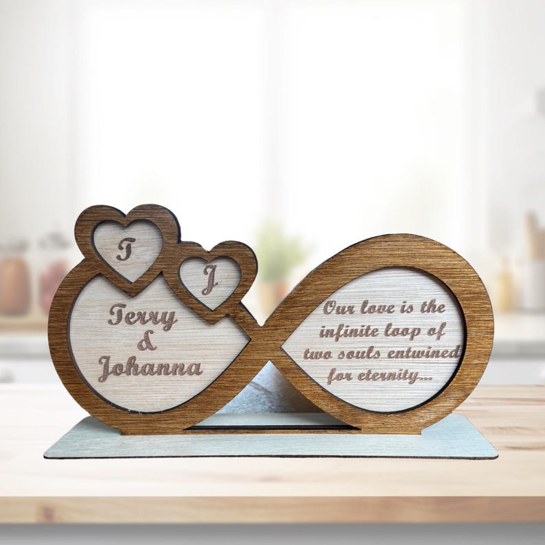 Puede incluir: S&iacute;mbolo de infinito de madera con dos corazones y los nombres Terry y Johanna grabados en &eacute;l. El s&iacute;mbolo de infinito tambi&eacute;n tiene el texto "Our love is the infinite loop of two souls entwined for eternity..." grabado en &eacute;l.