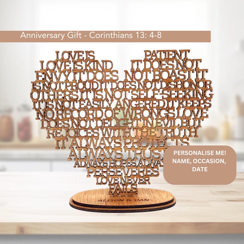 May include: Wooden heart-shaped anniversary gift with the text "Love is..." from Corinthians 13: 4-8. The heart sits on a round wooden base. The text "Personalise me! Name, occasion, date" is also visible.