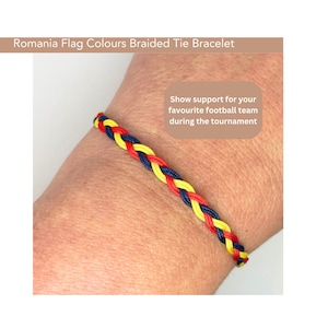 May include: A braided bracelet in the colours of the Romanian flag: yellow, blue, and red. The bracelet is tied on a person's wrist.