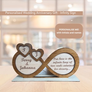 Puede incluir: Signo de infinito de madera con el texto "Nuestro amor es el bucle infinito de dos almas entrelazadas por la eternidad..." y personalizado con los nombres "Terry & Johanna" y las iniciales "T" y "J".