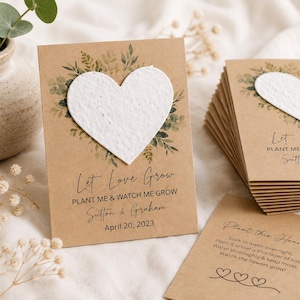 May include: Rectangular kraft paper cards featuring a white textured heart shape, green botanical illustrations, and the printed text Let Love Grow, PLANT ME & WATCH ME GROW, Sutton & Graham, and April 20, 2023, with planting instructions on the back.