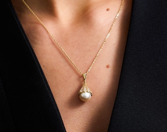 May include: A gold chain necklace with a pearl pendant. The pendant is surrounded by small clear stones.
