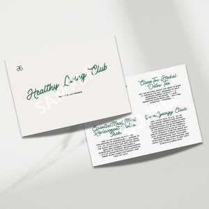 May include: White cards with green text promoting a healthy lifestyle. The cards include the text "Healthy Living Club," "Clean Tox Herbal Detox Tea," and "Essential Meal Replacement Protein Shake." The cards are on a white surface.