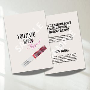 Pode incluir: Dois cartões rosa claro com texto preto e rosa. Um cartão diz "YOU HAVE BEEN Fizzed" com um carimbo de amostra. O outro cartão diz "OBTENHA O IMPULSO NATURAL QUE VOCÊ PRECISA PARA PASSAR O DIA!" Um pacote de palitos de "EnergyFizz" está no primeiro cartão.