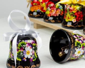 Puede incluir: Un conjunto de cinco campanas de madera pintadas de negro con diseños florales. Las campanas tienen cintas blancas y están decoradas con flores y hojas de colores.