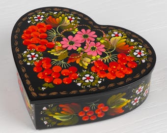 May include: A heart-shaped wooden box with a black background and hand-painted floral design. The design features red berries, pink flowers, and green leaves.