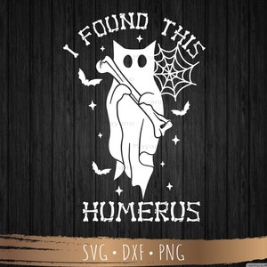May include: A white ghost holding a bone with a spiderweb behind it. The text "I found this humerus" is below the ghost and the text "SVG - DXF - PNG" is below that.