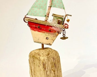 Hand crafted red and white wooden boat assemblage art ornament with turquoise sails decorated with reclaimed and found items