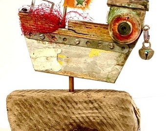Beautiful hand crafted wooden boat with orange flag made from reclaimed items and found objects, set on a piece of Scottish driftwood.