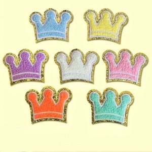 May include: Set of ten colorful felt crown patches with gold glitter trim. The crowns are in various colors including blue, yellow, purple, white, pink, orange, and green.