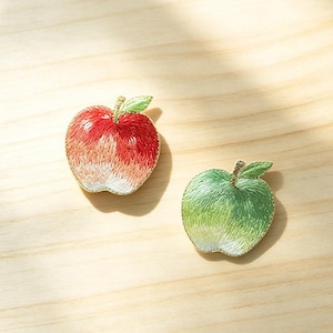 May include: Two embroidered apple patches with gold-toned edges. One apple features a gradient of red, orange, and white thread, while the other displays a gradient of green and white thread. Both have a small green leaf and the text Longancraft.