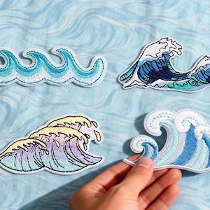 Op de afbeelding: Geborduurde golfpatches in verschillende kleuren, waaronder blauw, turquoise en geel. De patches hebben gedetailleerde stiksels en een witte rand. De afbeelding bevat de tekst "Longancraft" bovenaan.