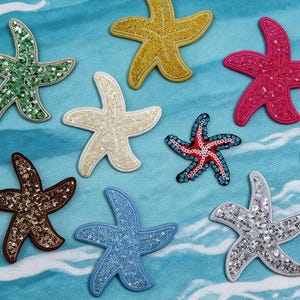 May include: A collection of sequined starfish patches in various colors, including green, yellow, pink, white, blue, brown, and silver. The patches are arranged on a blue and white patterned surface. The text "Longancraft" is displayed at the top.
