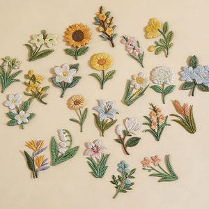 May include: A collection of embroidered floral patches in various colors, including yellow, white, pink, and blue. The patches feature detailed designs of sunflowers, lilies, and other flowers. The word "Longancraft" is displayed at the top.