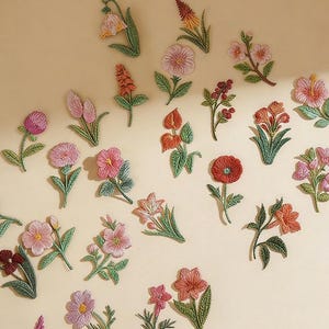May include: Embroidered floral patches in various colours, including pink, orange, and red, with green leaves. The patches are arranged on a beige background. The text "Longancraft" is at the top.