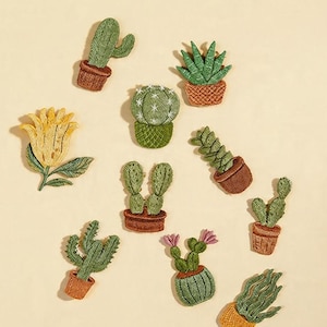 Puede incluir: Parches bordados de varios cactus y suculentas en macetas, incluyendo una flor amarilla. Los parches son verdes, marrones y amarillos, con costuras detalladas. El texto "Longancraft" está en la parte superior.