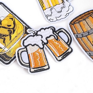 May include: Embroidered patches featuring beer mugs and a wooden barrel. The patches have a white border and depict frothy beer in shades of yellow and orange. The text "Longancraft" is at the top of the image.