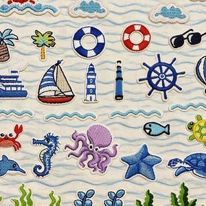 Może przedstawiać: Kolekcja haftowanych naszywek o tematyce morskiej. Wzory obejmują żaglówkę, latarnię morską, koła ratunkowe i różne stworzenia morskie, takie jak krab, konik morski i ośmiornica. U góry widnieje napis "Longancraft".