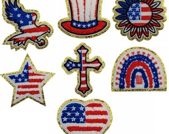Può includere: Una collezione di toppe ricamate patriottiche con disegni della bandiera americana. Include un'aquila, un cappello a cilindro, una stella, una croce, un cuore e un arcobaleno, tutti nei colori rosso, bianco e blu con bordi dorati.