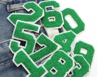 May include: Green felt iron-on numbers with white outlines. The numbers are 1, 2, 3, 4, 5, 6, 7, 8, 0. The numbers are on a blue denim background.