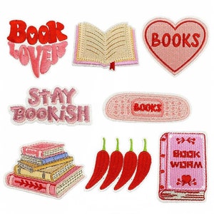 May include: Set of nine embroidered iron-on patches featuring book-themed designs. The patches are pink, red, and white with various designs including a book, a heart with the word "BOOKS", and a stack of books.