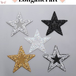 Peut inclure: Cinq patchs thermocollants en forme d'étoile avec des embellissements en strass. Les patchs sont en argent, or, noir et deux nuances de gris.