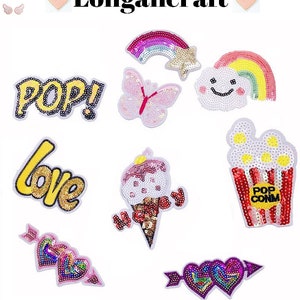 May include: Assortment of colorful iron-on patches featuring various designs, including a rainbow, butterfly, ice cream cone, popcorn, and the words "Pop!" and "Love".