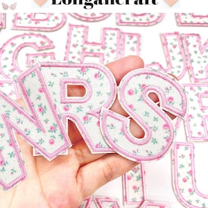 May include: Floral fabric letters with pink edging. The letters feature a white background with a pattern of small pink roses and green leaves. Various fonts and sizes are visible. The brand name "Longancraft" is displayed at the top.
