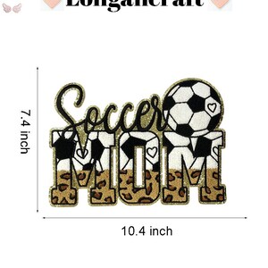 K&ouml;nnte beinhalten: Ein goldener Glitzer-Patch mit der Aufschrift "Soccer Mom" mit einem schwarz-wei&szlig;en Fu&szlig;ball und Leopardenmuster-Akzenten. Der Patch ist 7,4 Zoll hoch und 10,4 Zoll breit.