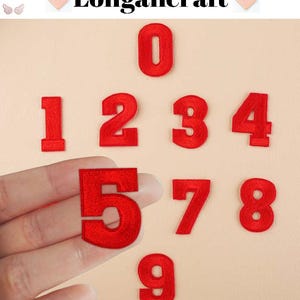 Może przedstawiać: Zbiór czerwonych, haftowanych cyfr od 0 do 9, na beżowym tle. Cyfra 5 jest trzymana w dłoni. Marka "Longancraft" znajduje się na górze. Te naszywki są idealne do rękodzieła i personalizacji.