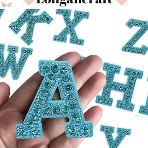 May include: Close-up of the letter "A" in a light blue color, encrusted with sparkling rhinestones. Other letters are visible in the background. The word "Longancraft" is at the top of the image.