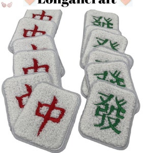 May include: A set of 10 white mahjong tiles with red and green embroidered characters. The tiles are arranged in two stacks, with the red characters on the left and the green characters on the right.