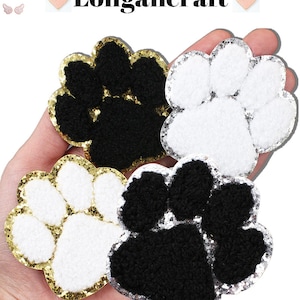 May include: Four paw print iron-on patches. Two are black with gold glitter trim, one is white with gold glitter trim, and one is white with silver glitter trim.